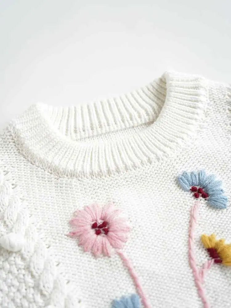 White knitted baby girls sweater with hand-embroidered floral details in pink blue and yellow floral cotton by trend den
