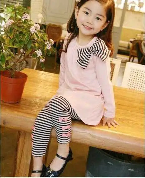 Pink girls bow accent tunic with black and white striped bow paired with striped leggings from trend den