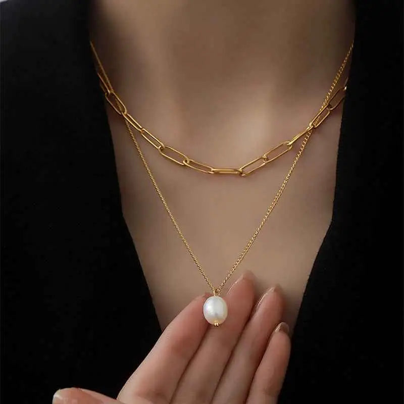 Lumina layered gold necklace featuring a bold paperclip chain and delicate freshwater pearl pendant in layered gold chain style