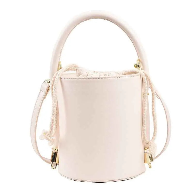 A sleek blush pink leather-like cylinder bucket bag with drawstring inner and gold-tone hardware from trend den White