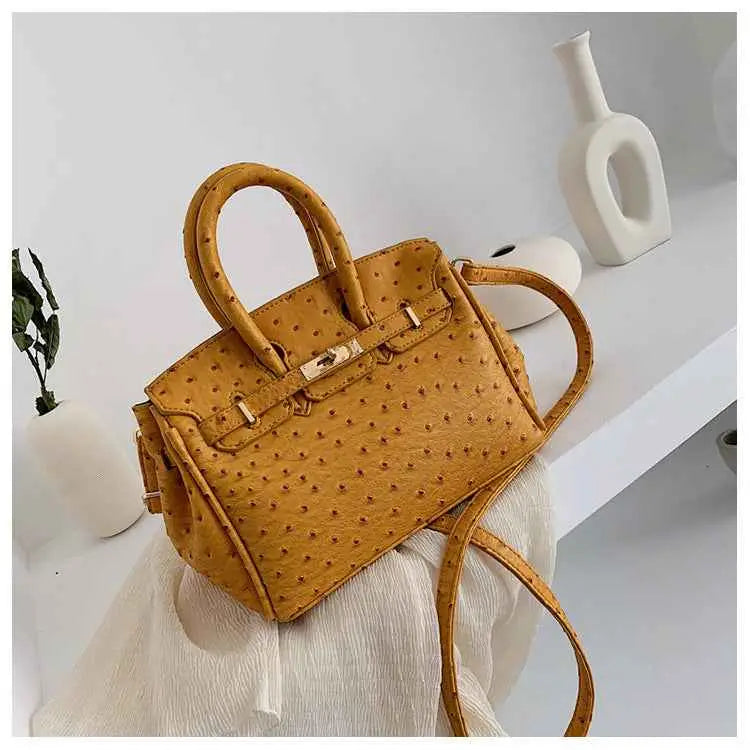 A mustard-yellow structured ostrich-pattern handbag with gold-tone hardware made from durable polyester yellow