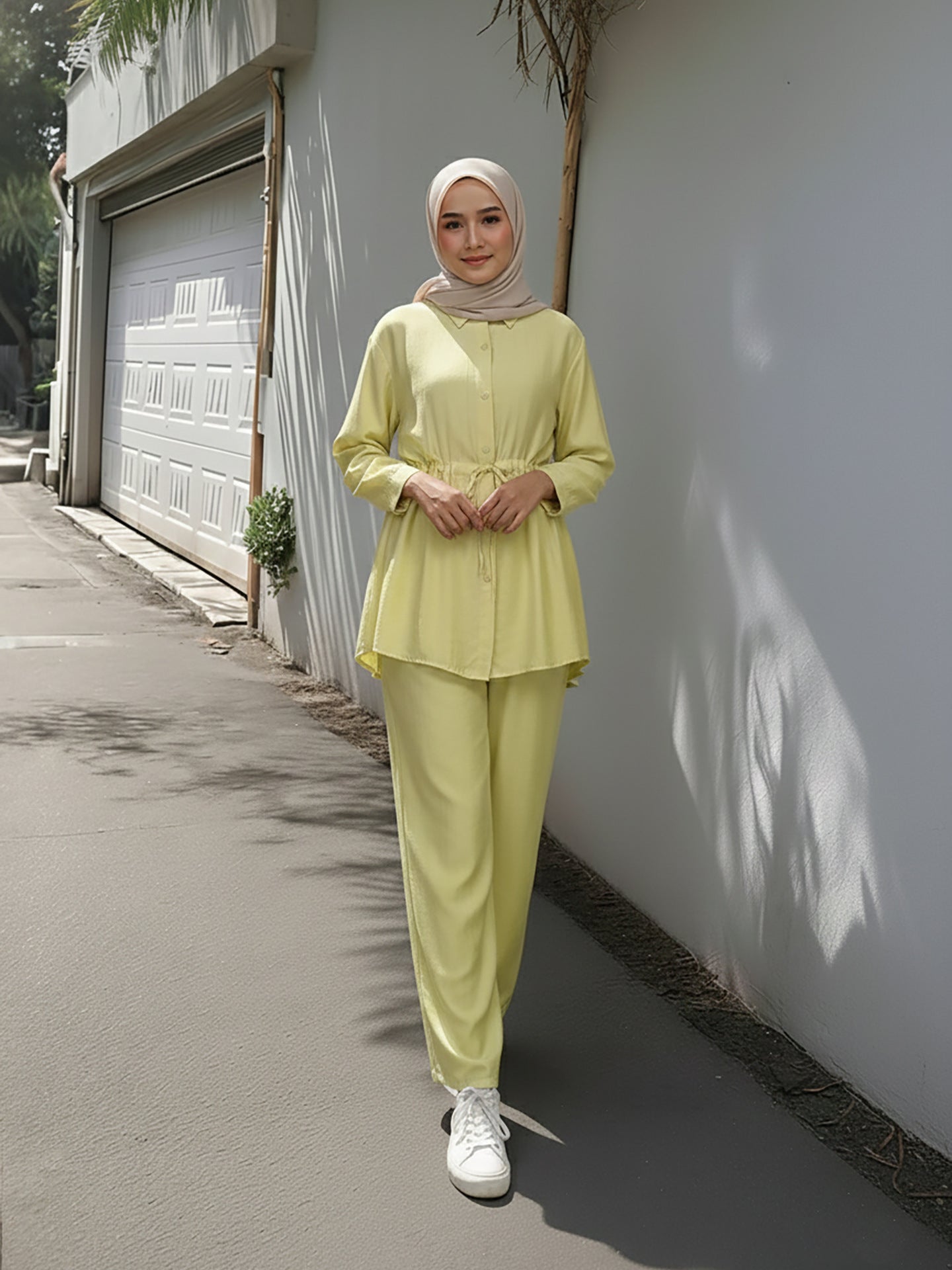 Woman in a light green outfit standing against a white wall. Bright Yellow