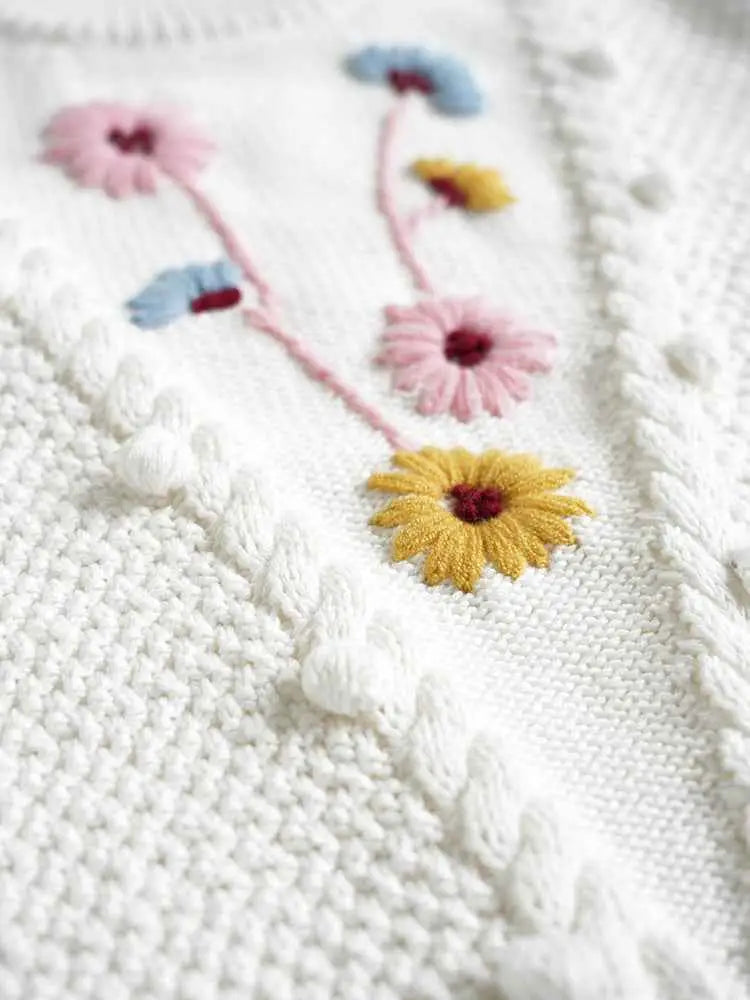 Baby girls white knitted sweater with hand-embroidered floral pink yellow and blue flowers on floral cotton fabric