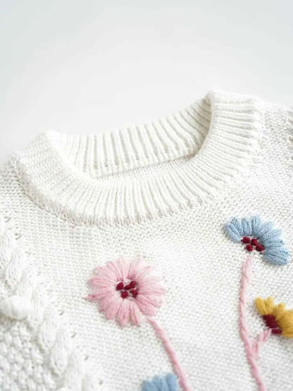 White knitted baby girls sweater with hand-embroidered floral details in pink blue and yellow floral cotton by trend den