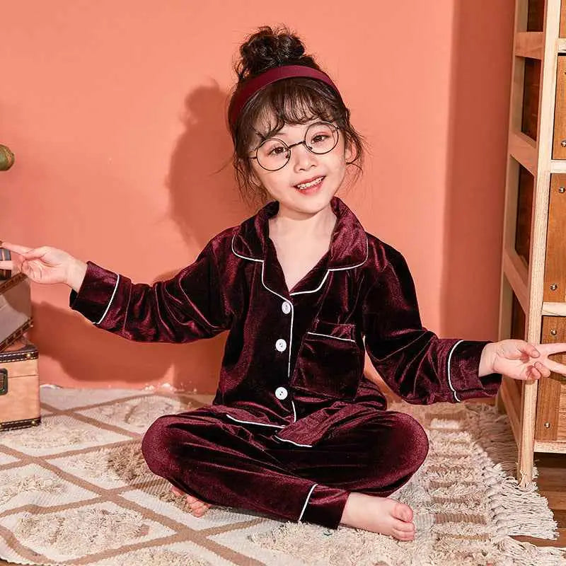 A child wearing a deep burgundy velvet pajama set with white piping from trend den gold velvet pajama set collection