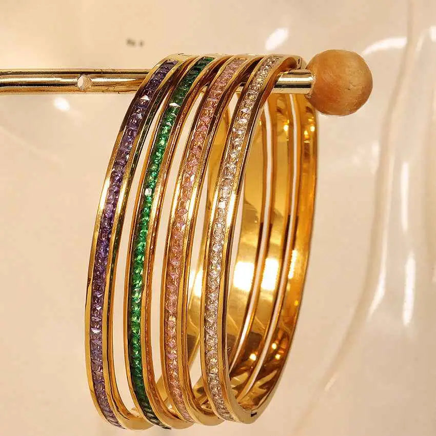 A set of five gold stainless steel crystal inlaid slim bangles with colorful gemstones in an elegant stacked design