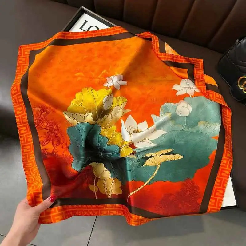 Vibrant orange dopamine-print silk feel square scarf with detailed white lotus floral design and teal leaves from trend den Lotus Pond Tangerine