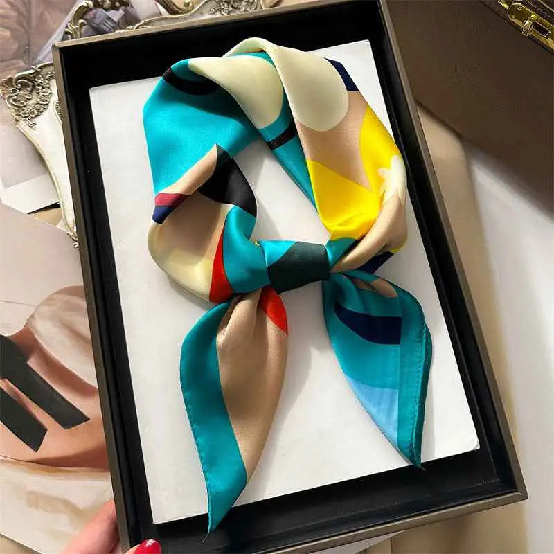 A vibrant dopamine-print silk feel square scarf in teal yellow beige and black tied into a neat bow