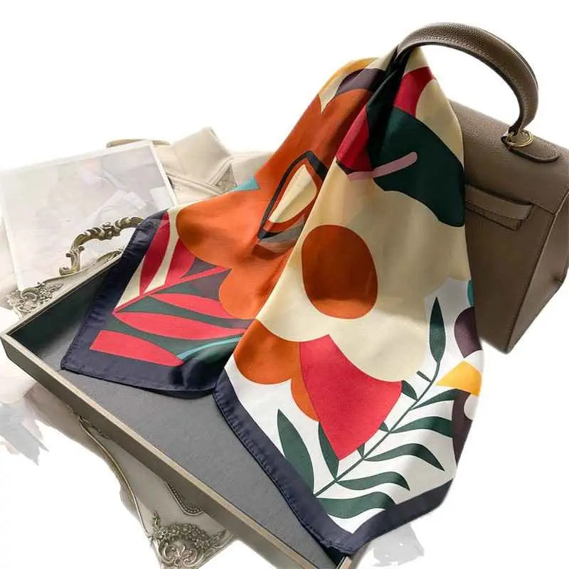 A vibrant dopamine-print silk feel square scarf with bold orange red and green blooms on a cream background