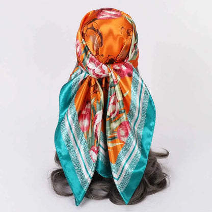 Elegant oversized 90cm x 90cm floral imitation silk scarf in vibrant orange and teal tied as a headscarf by trend den