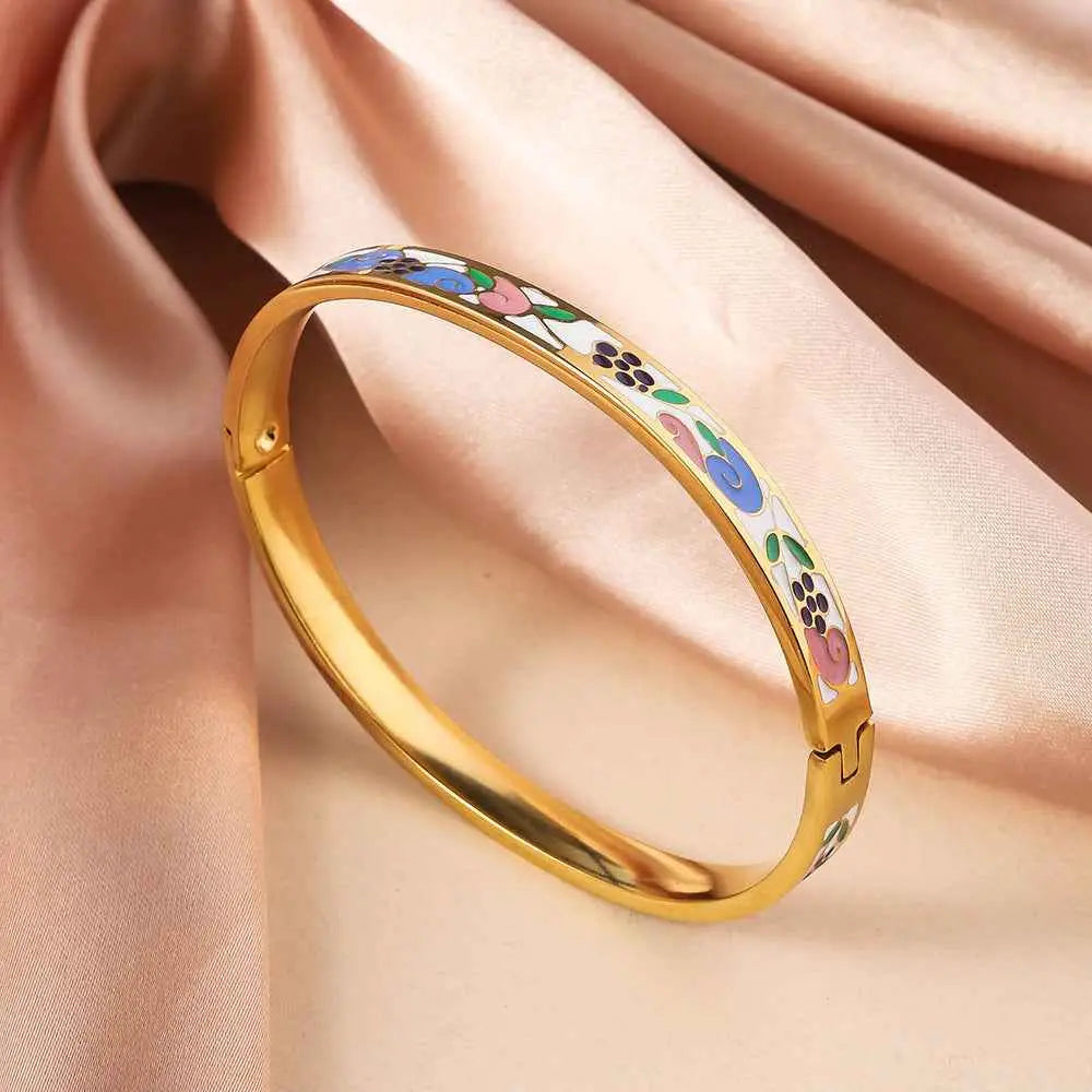 Gold bangle bracelet in titanium steel with intricate blue pink green purple floral enamel designs on white background White Green Pink
