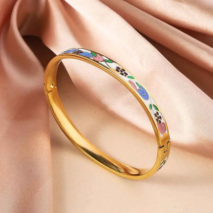 Gold bangle bracelet in titanium steel with intricate blue pink green purple floral enamel designs on white background White Green Pink
