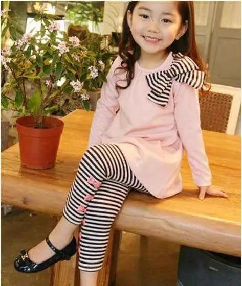 Pink long-sleeved girls bow accent tunic with black and white striped bow paired with striped leggings from trend den