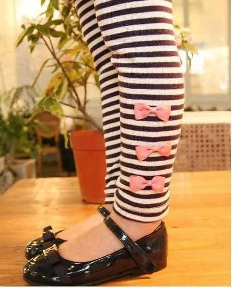 Girls bow accent tunic set featuring black and white striped leggings with three pink bow details from trend den