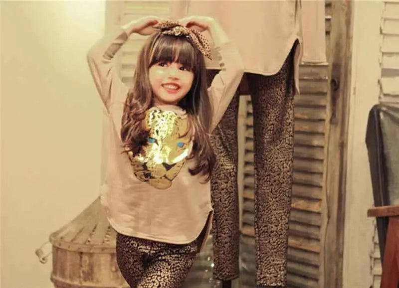 A child wearing a beige girls leopard print t-shirt and matching leggings with shiny gold leopard print design
