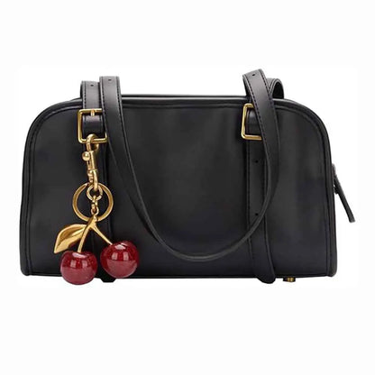 Black leather handbag with gold-tone hardware and glossy cherry bag charm made of zinc alloy from trend den