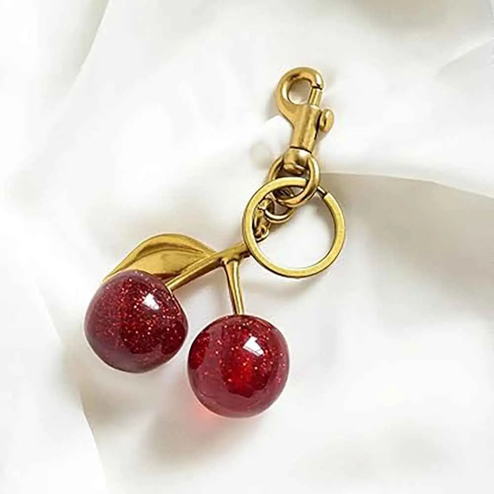 Gold-toned zinc alloy keychain with glossy red cherry charms and glittery leaf for trend den bag charm accessory