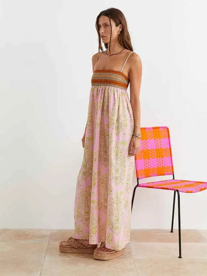 A flowing pink printed large swing dress with a gold intricate pattern and embroidered orange brown band at the bodice
