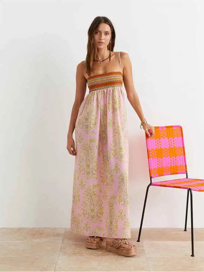 A flowing pink printed large swing dress with gold paisley patterns and an orange-brown embroidered bodice band