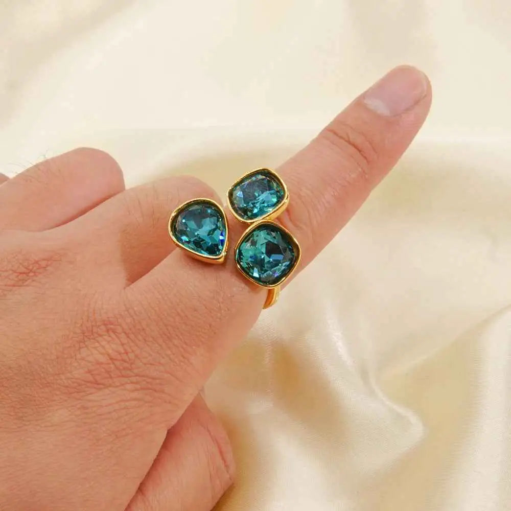 Gold-toned luxury multi-stone zircon ring with teal teardrop and square cut gemstones in stainless steel trend den design