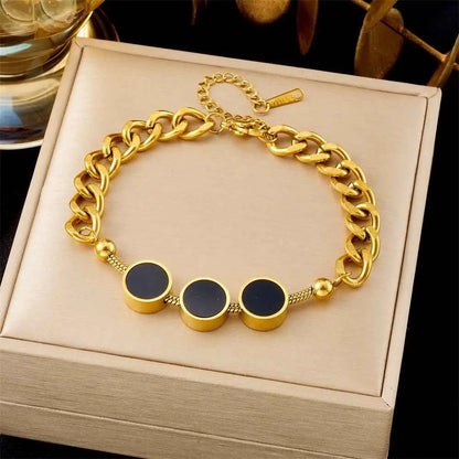Gold chain bracelet with black circular charms on a beige jewelry box. 5272 Three Black Circle