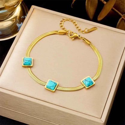 Gold bracelet with turquoise stones on a beige jewelry box 5292 Three Malachite