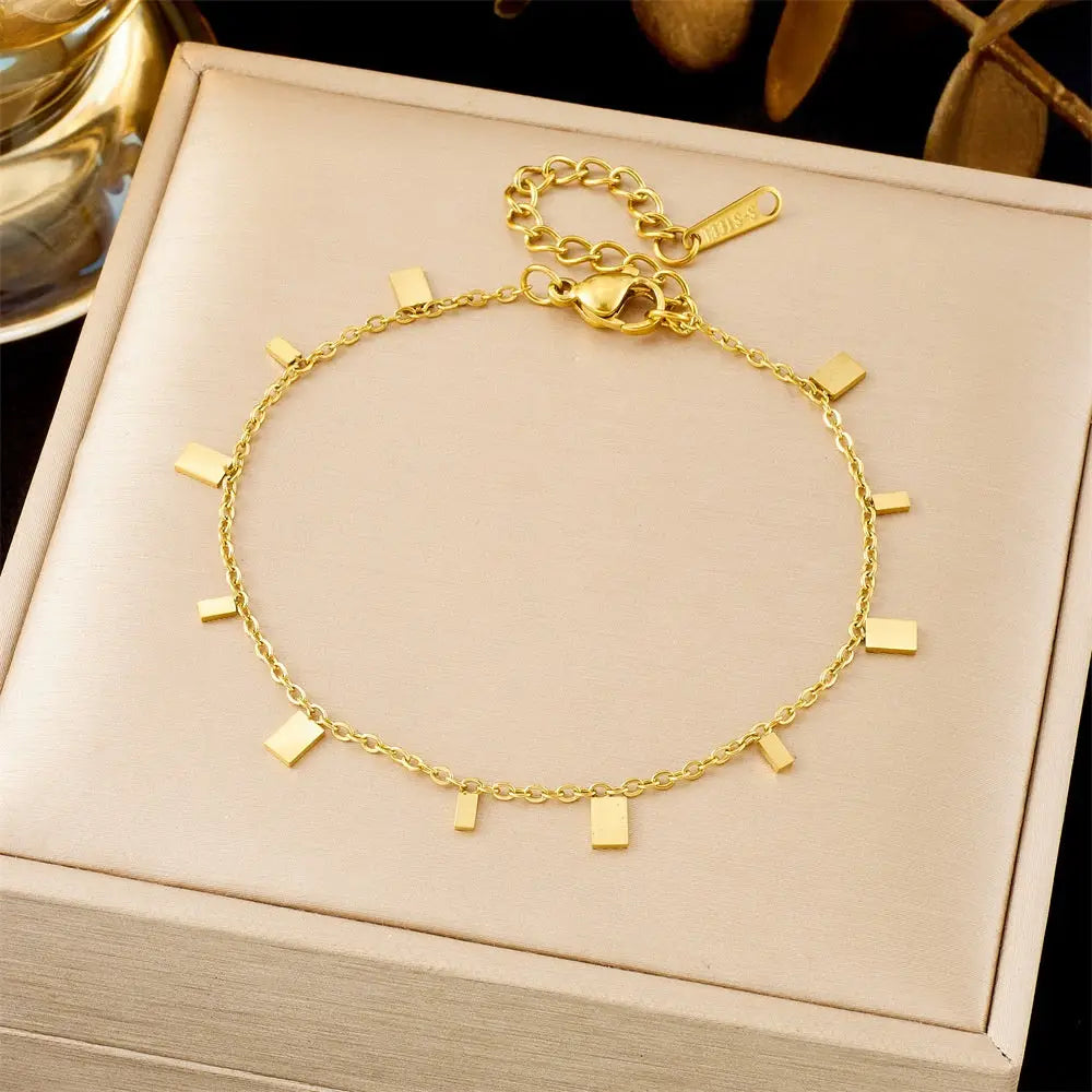 Gold bracelet with square charms on a beige jewelry box 5368 Square Piece