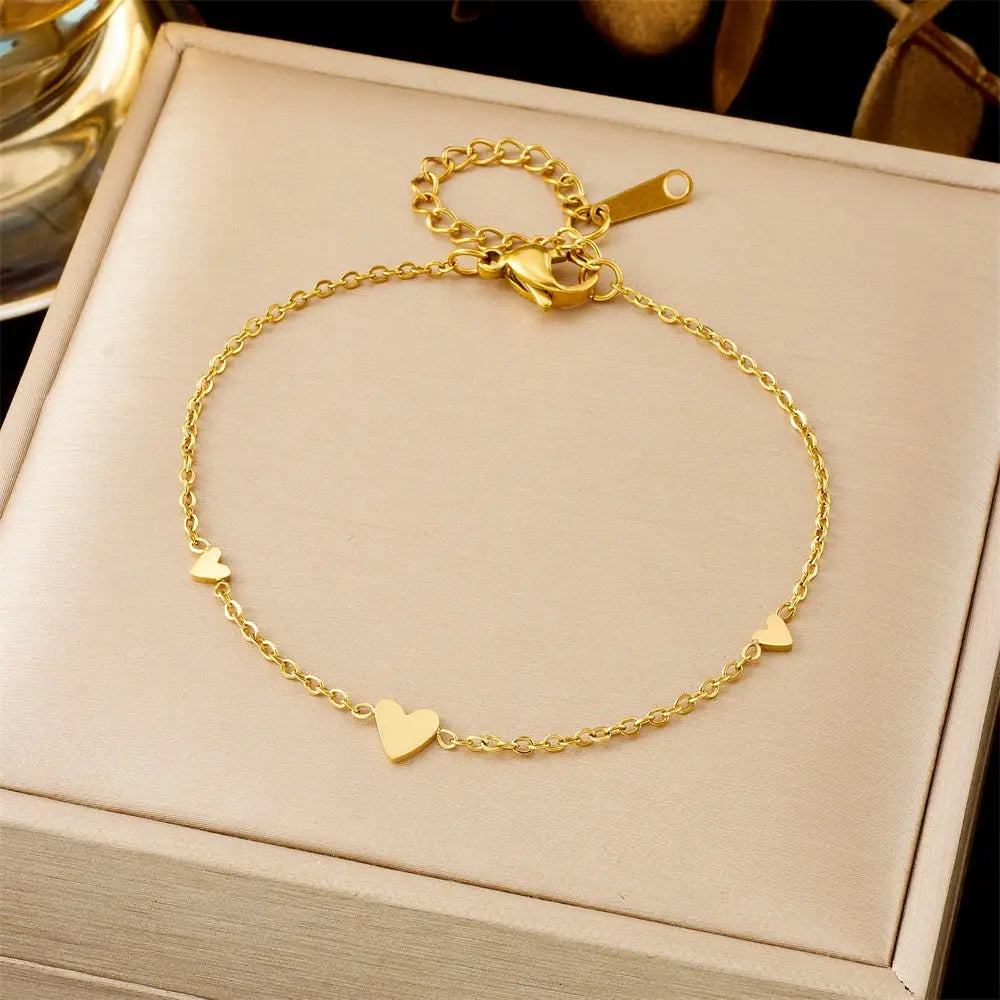 Trend Dens Gold bracelet with heart charms on a beige jewelry box 551 Three Hearts