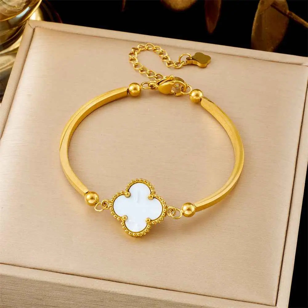 Gold-toned titanium steel fashion bracelet with white clover pendant and spherical accents in trend den box