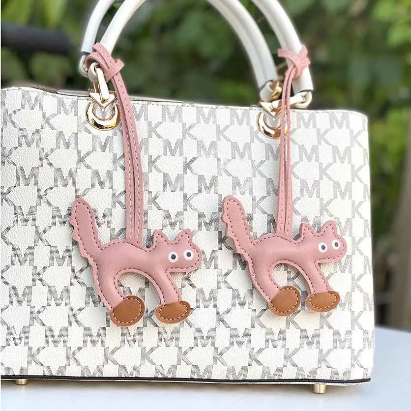 White mini cat bag with gray mk monogram and two pink cat bag charms from trend den collection