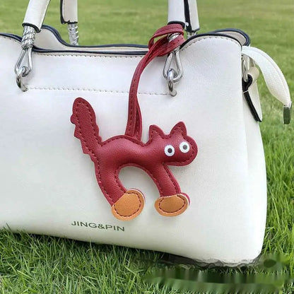 Red leather mini cat bag charm with white eyes and tan paws attached to a white handbag for trend den style Wine Red