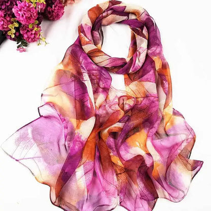 A flowing sheer georgette sunscreen scarf with vibrant oil painting floral leaf pattern in purple orange and cream A