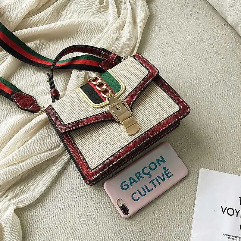 A stylish plaid satchel with snake trim, woven beige body, red leather accents, and a green-and-red webbing strap