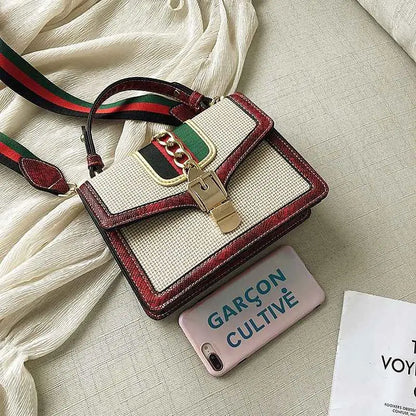 A stylish plaid satchel with snake trim, woven beige body, red leather accents, and a green-and-red webbing strap