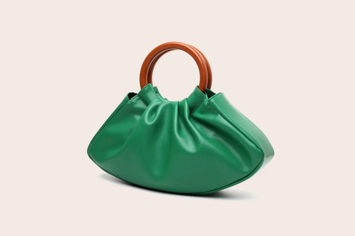 Vibrant green satin-finish pleated shell-shaped handbag with sleek rounded silhouette and warm brown wooden handle from trend den Green