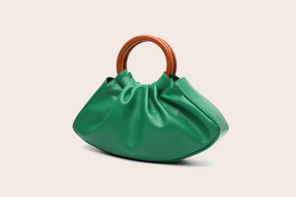 Vibrant green satin-finish pleated shell-shaped handbag with sleek rounded silhouette and warm brown wooden handle from trend den Green