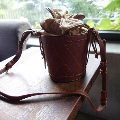 Brown quilted leather bucket bag with drawstring top and adjustable strap from trend den quilted base collection