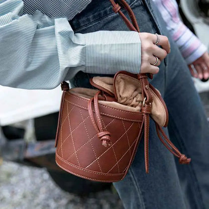 Brown quilted leather bucket bag with quilted base and drawstring closure from trend den with tan interior lining