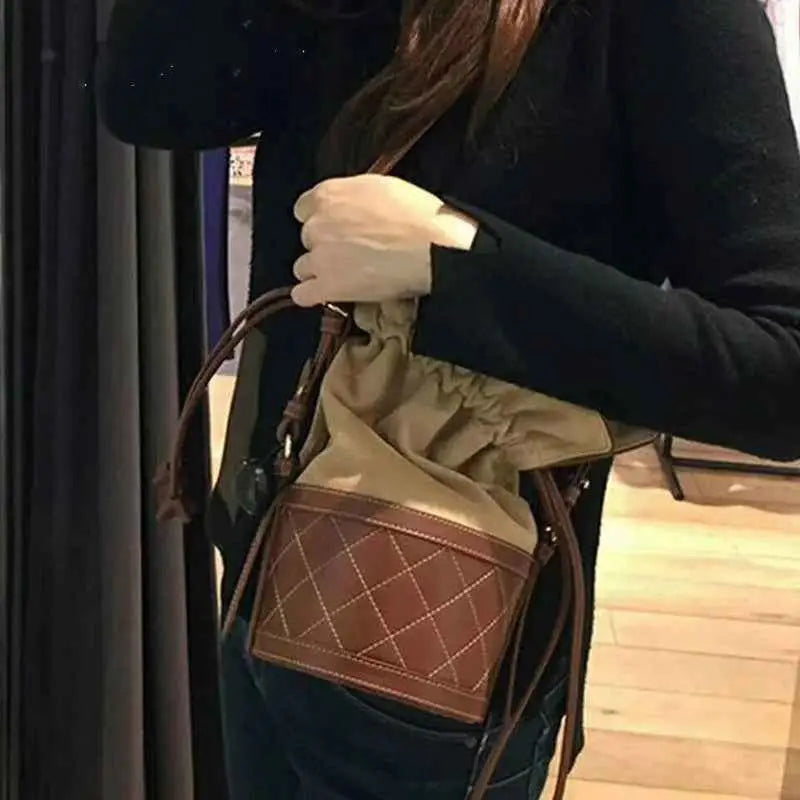 Brown quilted leather bucket bag with beige drawstring top and straps featuring a quilted base from trend den