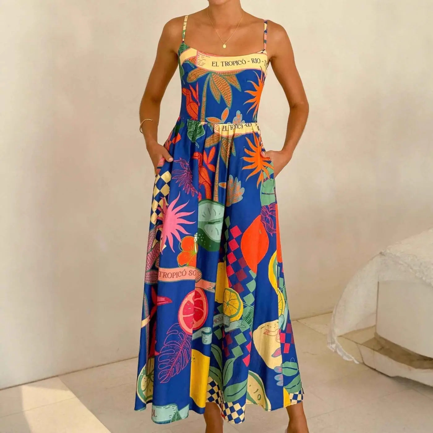A vibrant blue south african linen print slip dress with colorful fruit patterns and thin straps for casual holiday style