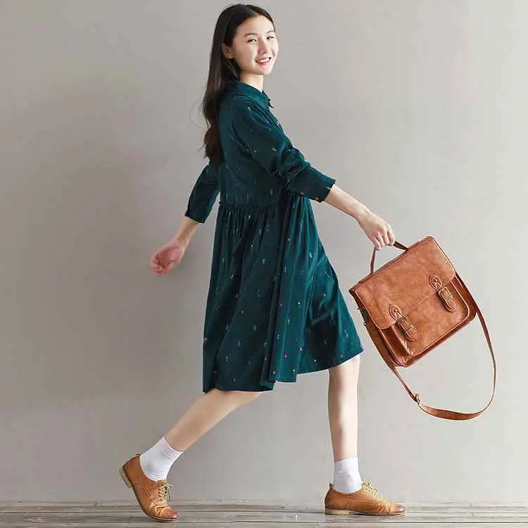 Brown leather satchel with flap and buckle closure complementing the long sleeve printed corduroy dress design