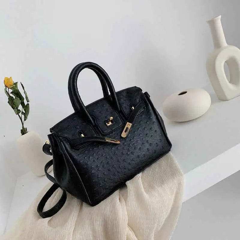 Structured ostrich-pattern handbag in black with gold-tone hardware and top handles made from durable polyester black