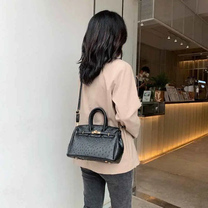 Black ostrich-pattern handbag with gold-tone hardware and top handles made of durable polyester from trend den