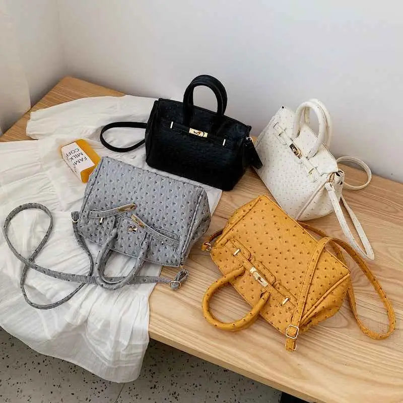 A structured ostrich-pattern handbag collection in black white gray and mustard yellow with durable polyester and gold hardware black