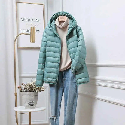 Ultra-lightweight women’s hooded down jacket in light teal with white duck fill and soft padded texture from trend den