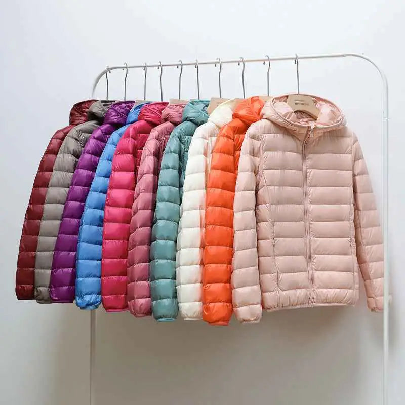 A row of ultra-lightweight women’s hooded down jackets in pink orange blue and purple made with white duck down on trend den rack
