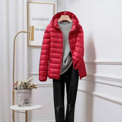 Vibrant red quilted ultra-lightweight women’s hooded down jacket made with white duck down on wooden hanger from trend den Red