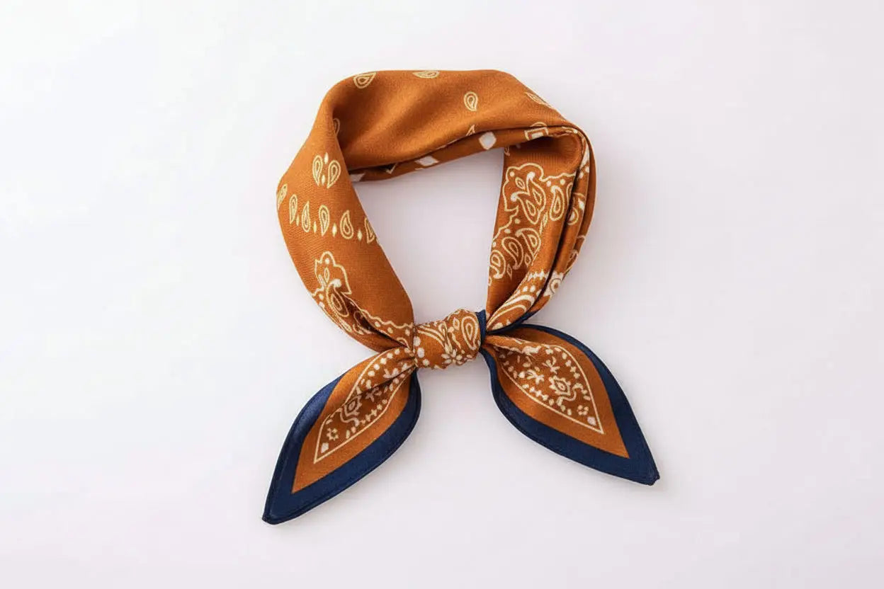 Rust-colored emulation silk bandana with cream paisley vintage print and navy trim tied in a neat knot from trend den