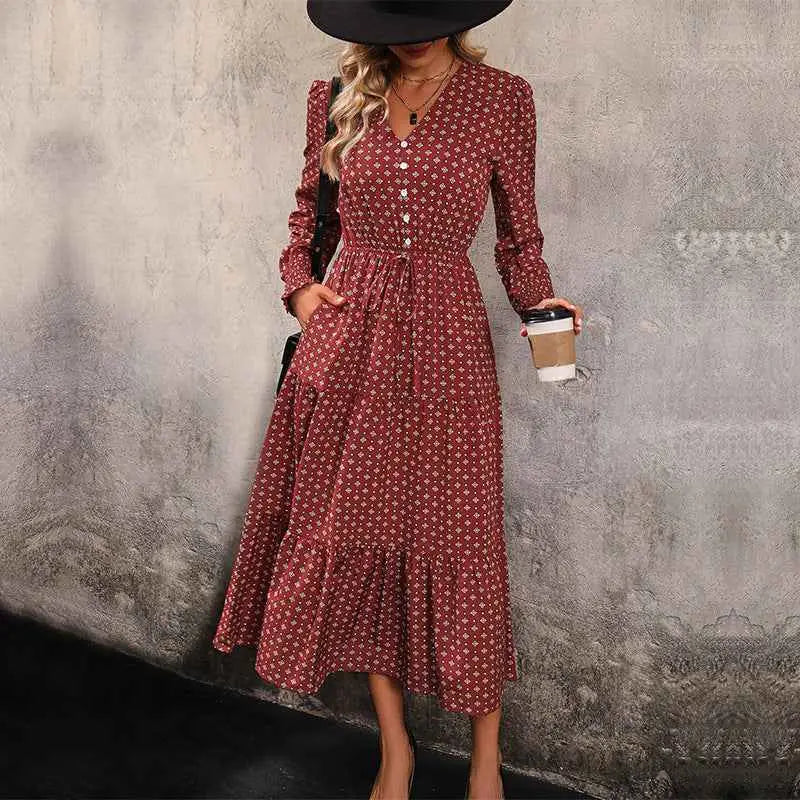 A woman wearing a red long sleeve printed autumn dress with white floral patterns and a fitted waistband