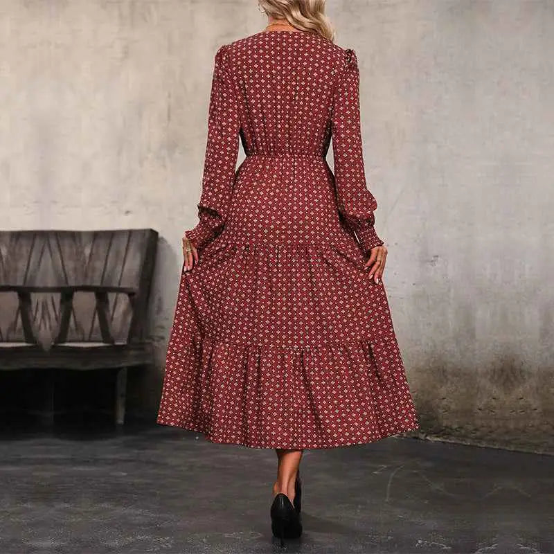 A woman wearing a long sleeve burgundy printed autumn dress with a subtle white geometric print and tiered skirt
